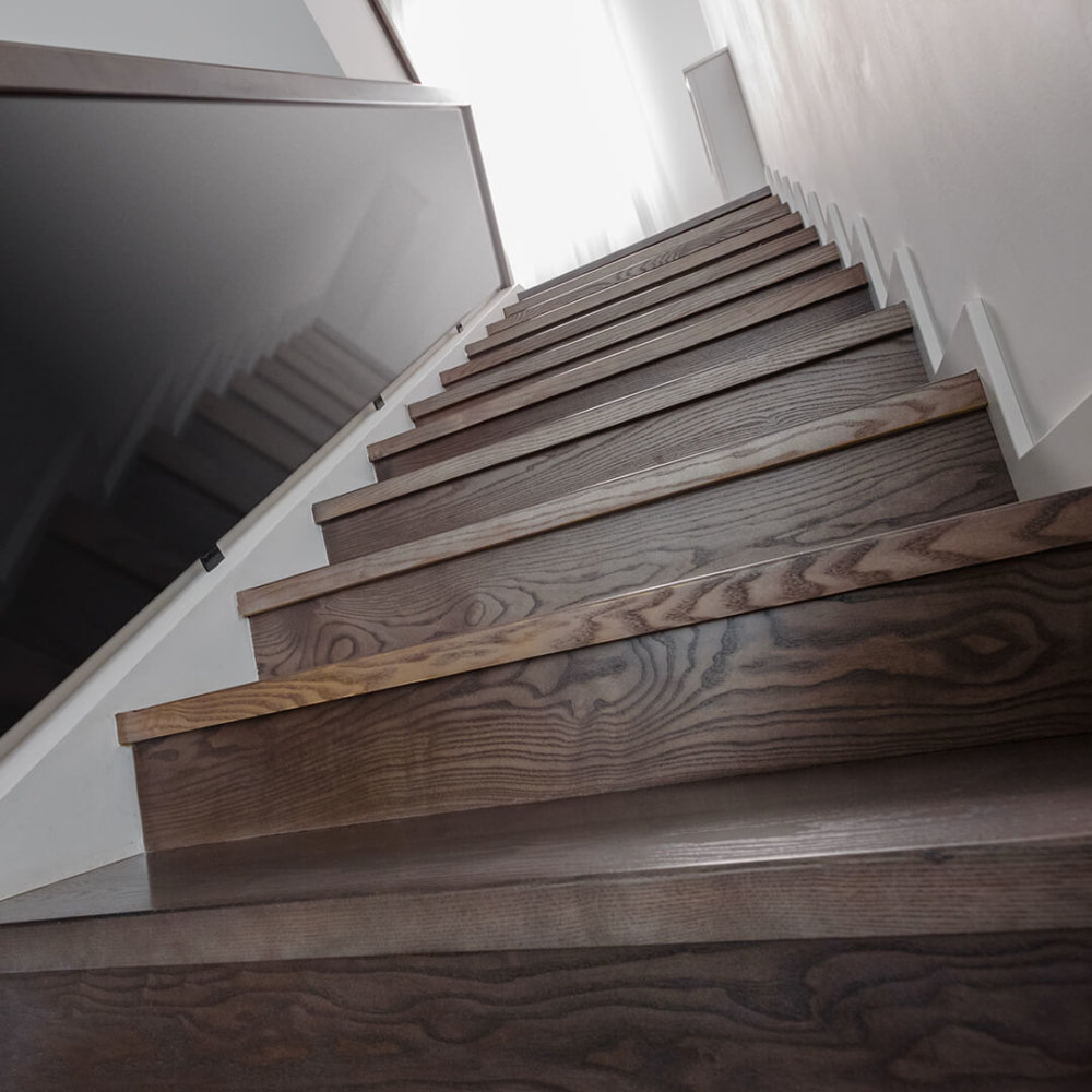 Hardwood stair nosing with tinted glass railing.